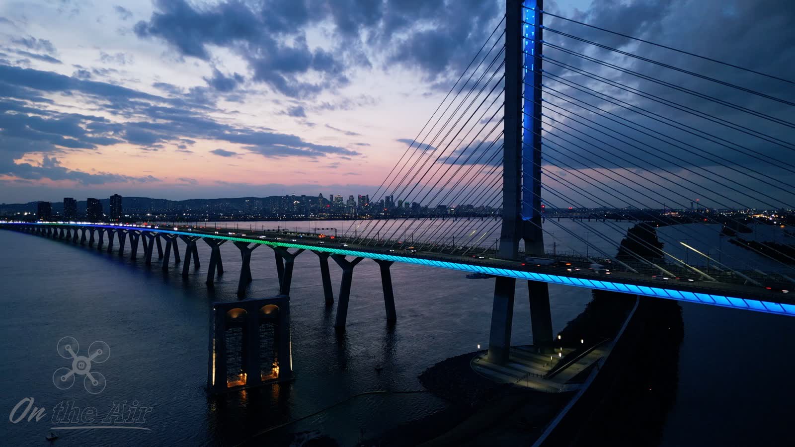 Samuel De Champlain Bridge lit at dusk, with downtown Montreal behind